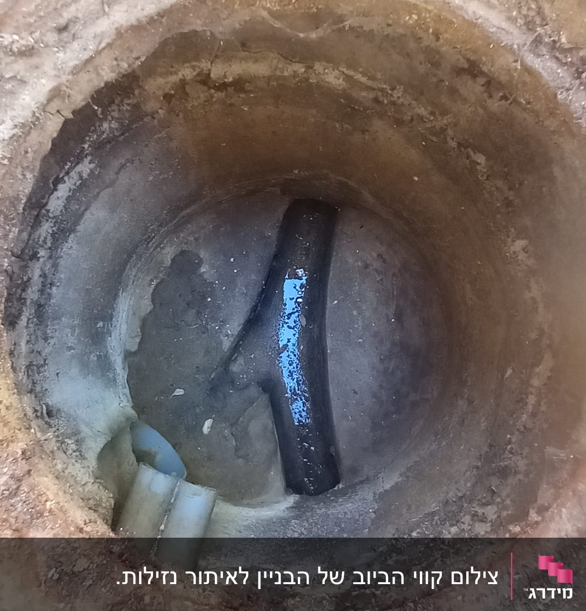צינור שבור בתוך בור בטון עם חלודה